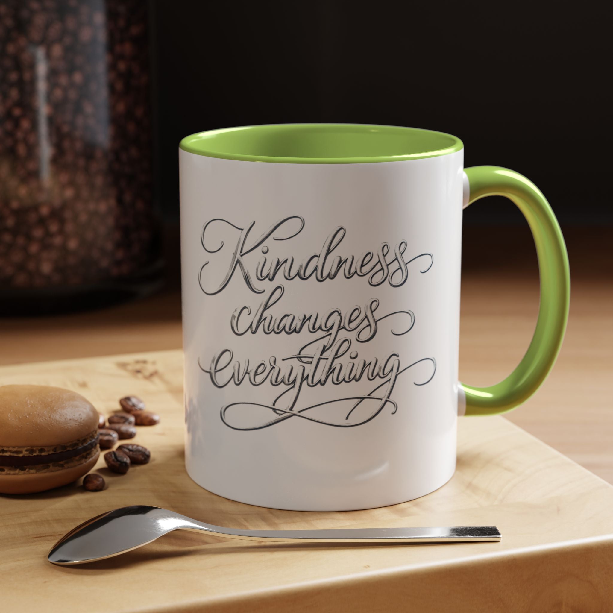 Inspirational ceramic accent coffee mug featuring elegant silver hand-lettered “Kindness Changes Everything” typography with colorful handle and interior accents.