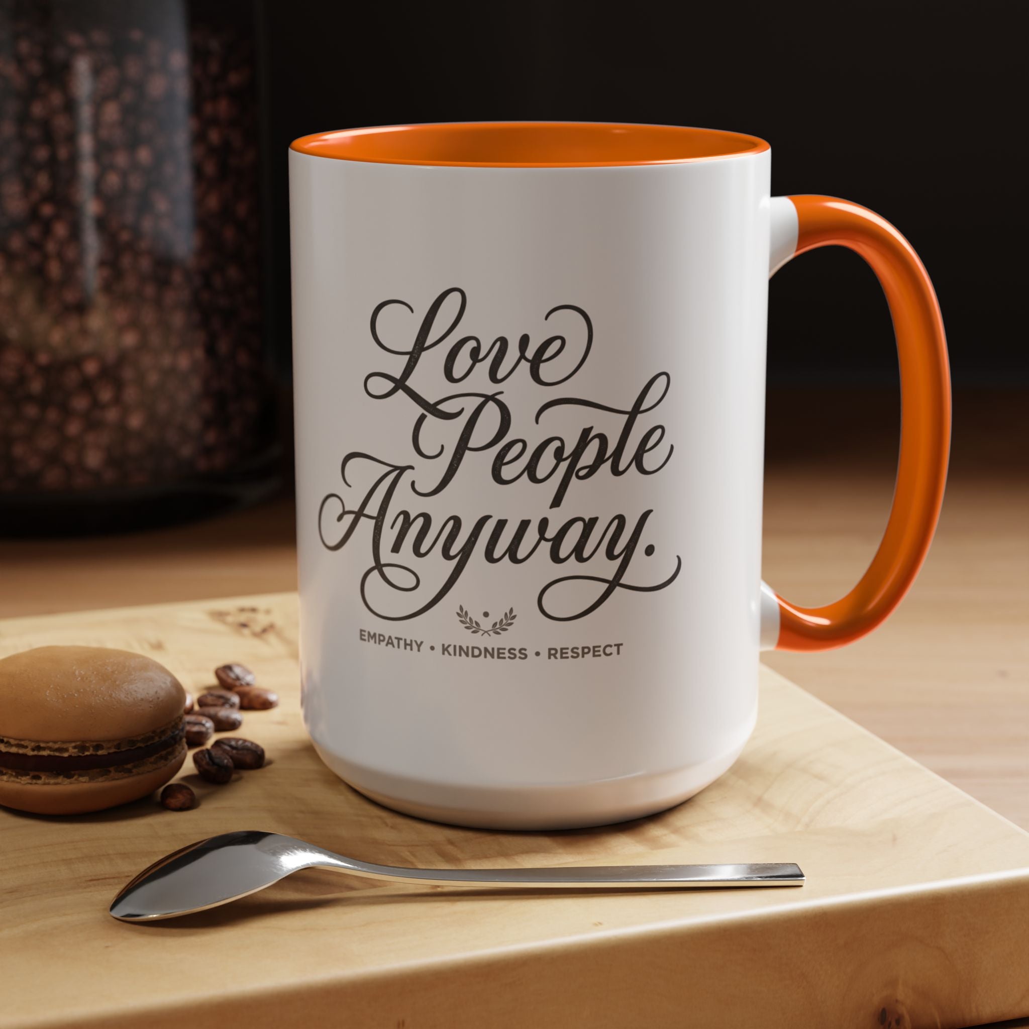 Inspirational ceramic accent coffee mug featuring hand-lettered “Love People Anyway” typography with empathy, kindness, and respect message on a glossy white mug with colorful handle and interior.