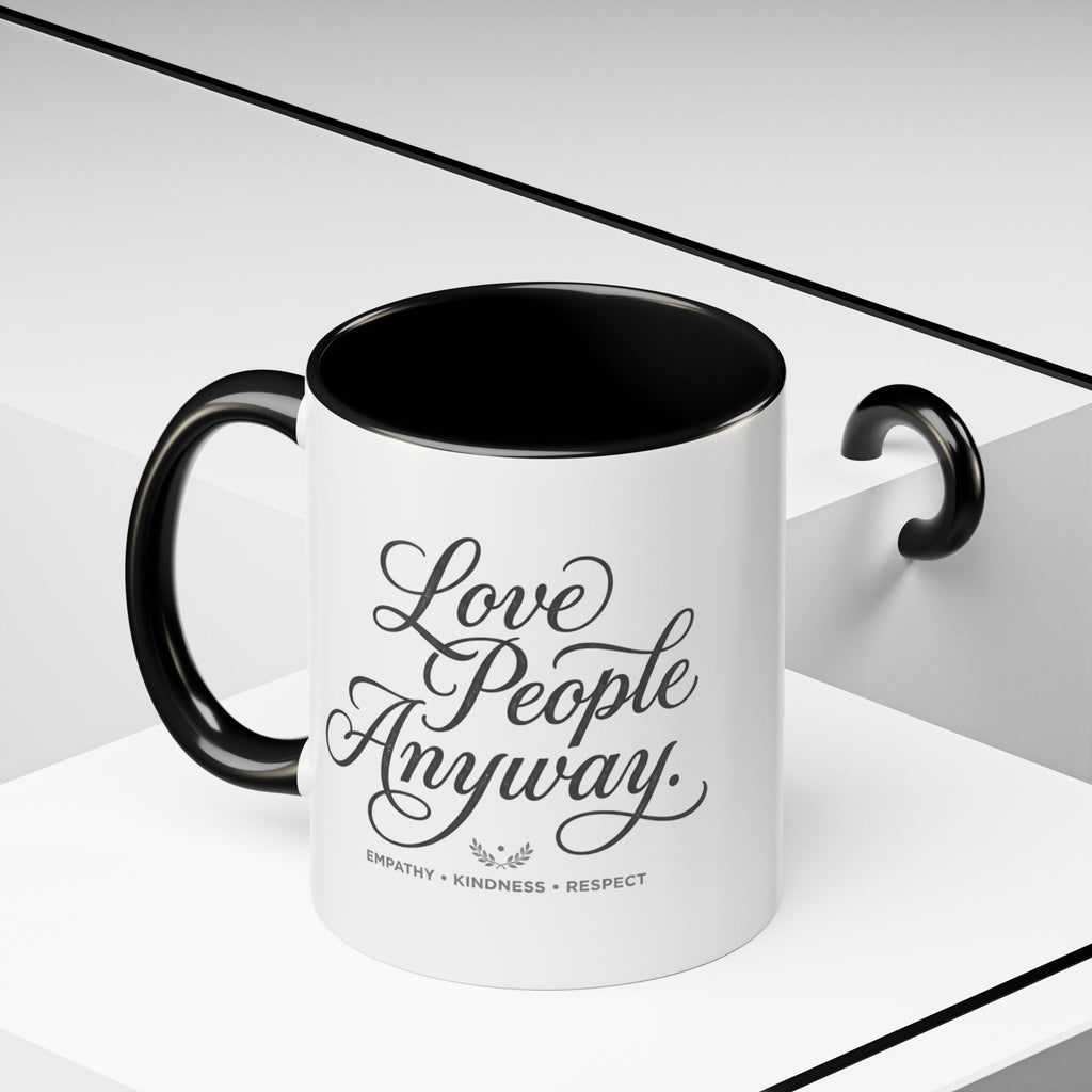 Inspirational ceramic accent coffee mug featuring hand-lettered “Love People Anyway” typography with empathy, kindness, and respect message on a glossy white mug with colorful handle and interior.