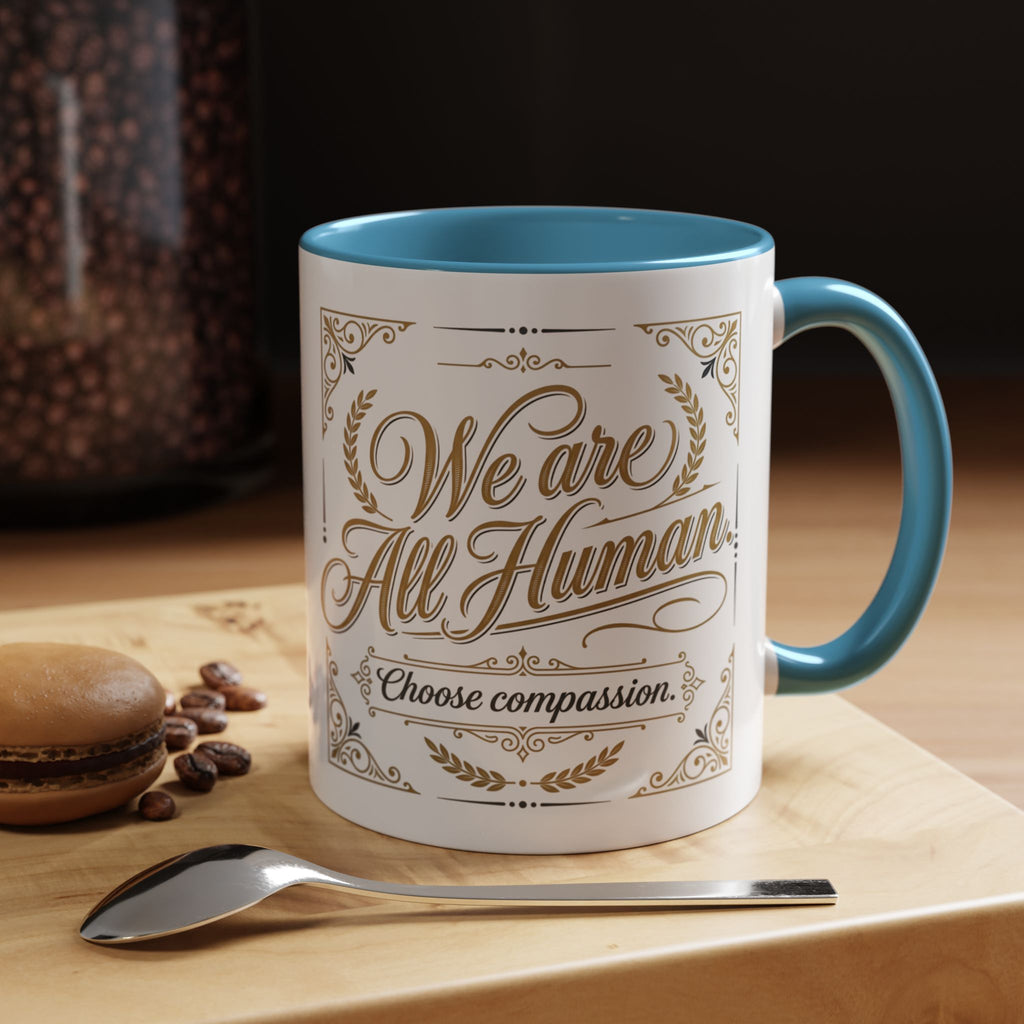 Inspirational ceramic accent coffee mug featuring “We Are All Human – Choose Compassion” in vintage-style gold lettering with decorative flourishes and black accent handle and interior.