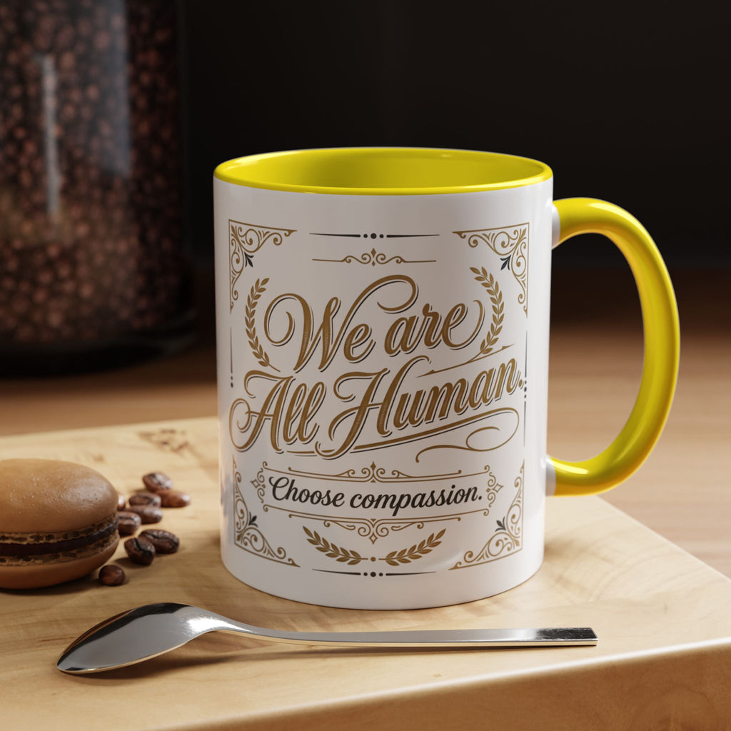 Inspirational ceramic accent coffee mug featuring “We Are All Human – Choose Compassion” in vintage-style gold lettering with decorative flourishes and black accent handle and interior.