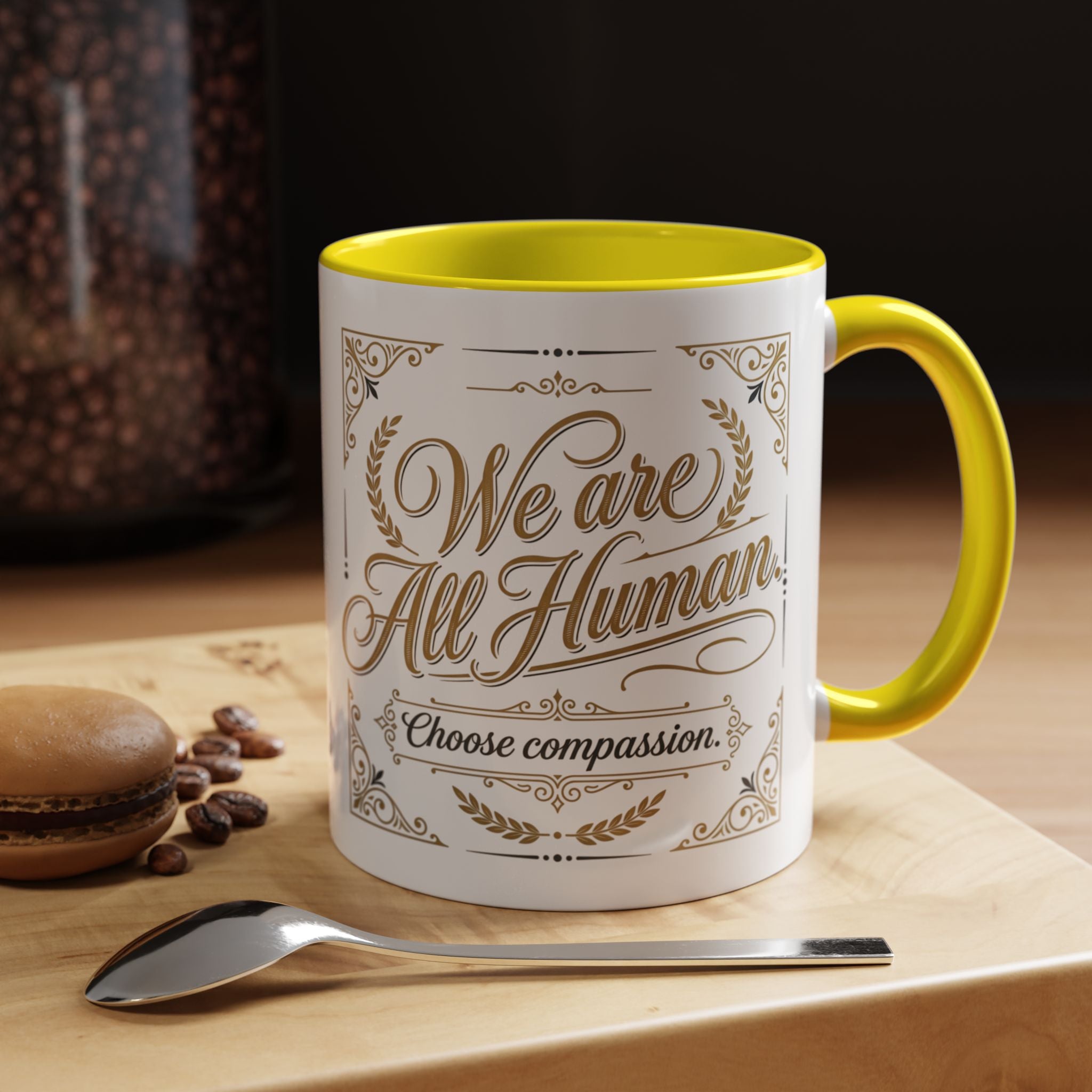 Inspirational ceramic accent coffee mug featuring “We Are All Human – Choose Compassion” in vintage-style gold lettering with decorative flourishes and black accent handle and interior.