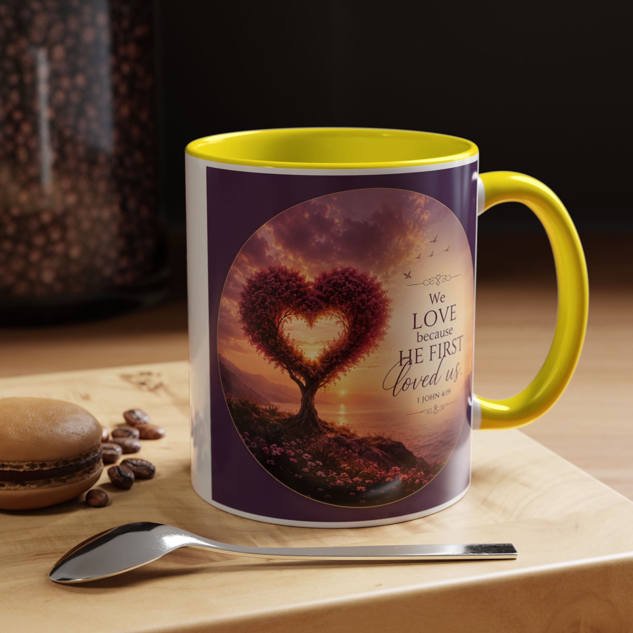 Inspirational Christian coffee mug featuring a glowing heart-shaped tree at sunset with the scripture “We Love Because He First Loved Us” from 1 John 4:19 and contrasting black handle and interior.