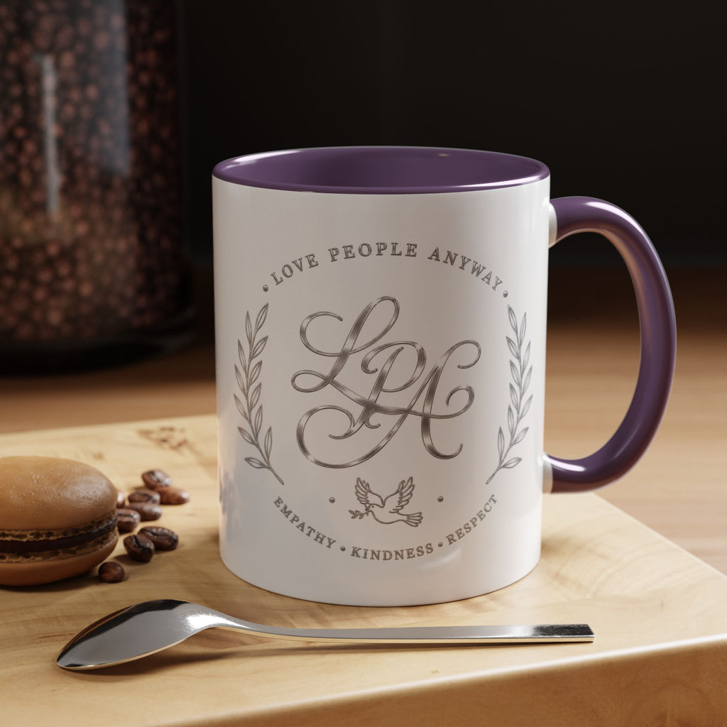 Inspirational ceramic coffee mug featuring silver “Love People Anyway” script, elegant monogram styling, decorative wreath accents, and contrasting handle and interior.