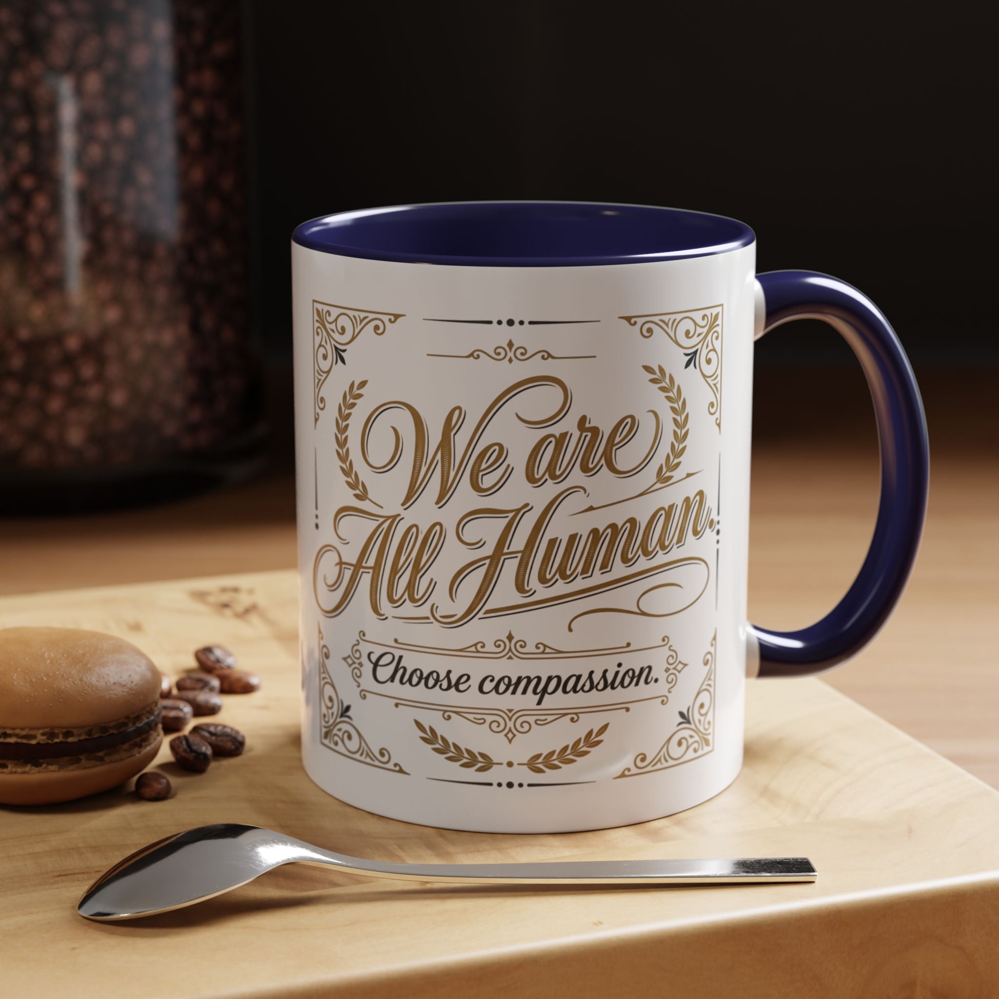 Inspirational ceramic accent coffee mug featuring “We Are All Human – Choose Compassion” in vintage-style gold lettering with decorative flourishes and black accent handle and interior.