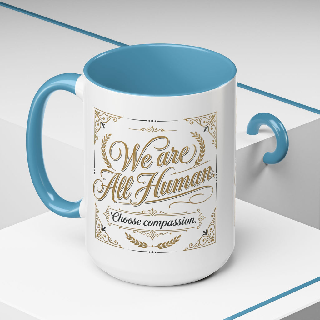 Inspirational ceramic accent coffee mug featuring “We Are All Human – Choose Compassion” in vintage-style gold lettering with decorative flourishes and black accent handle and interior.