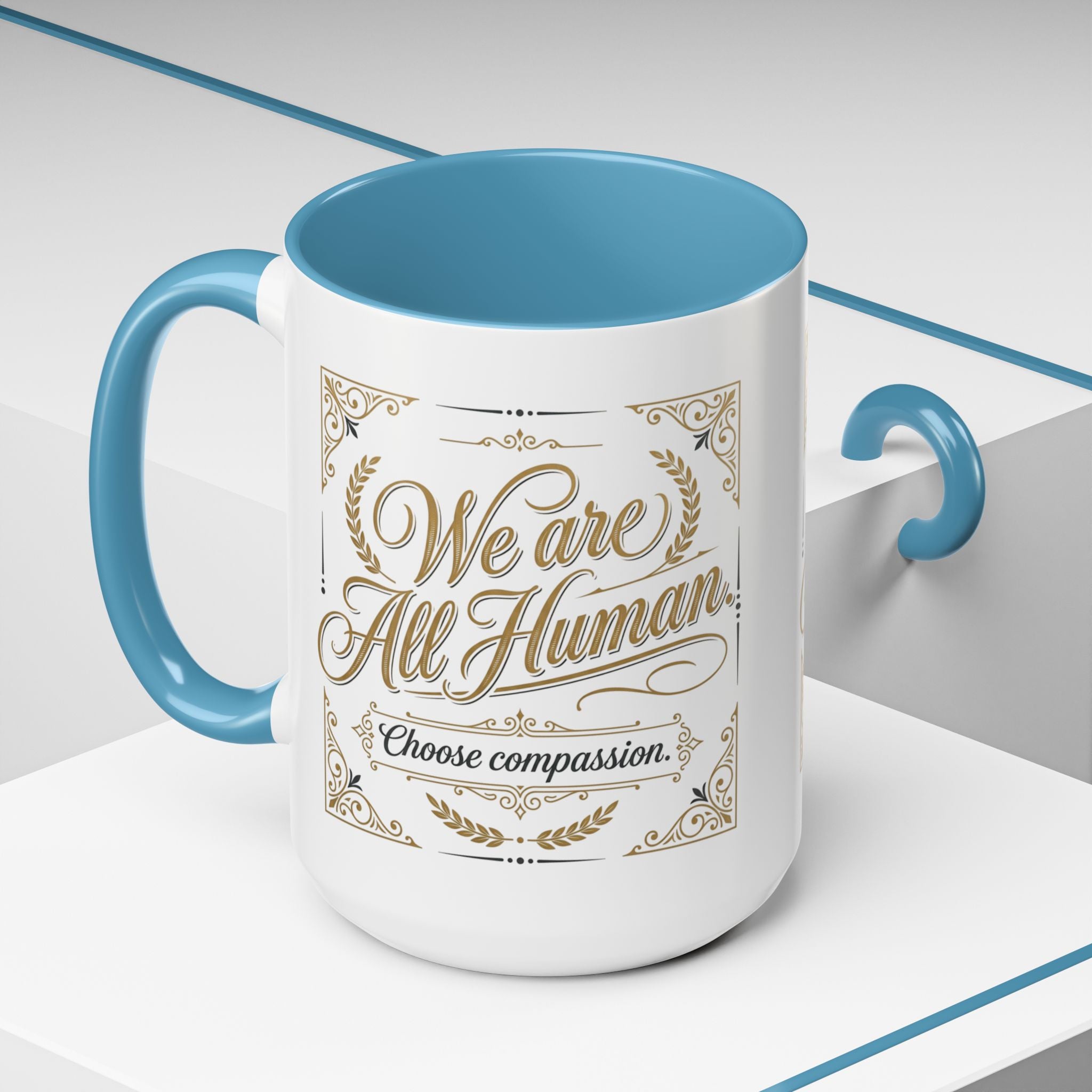 Inspirational ceramic accent coffee mug featuring “We Are All Human – Choose Compassion” in vintage-style gold lettering with decorative flourishes and black accent handle and interior.
