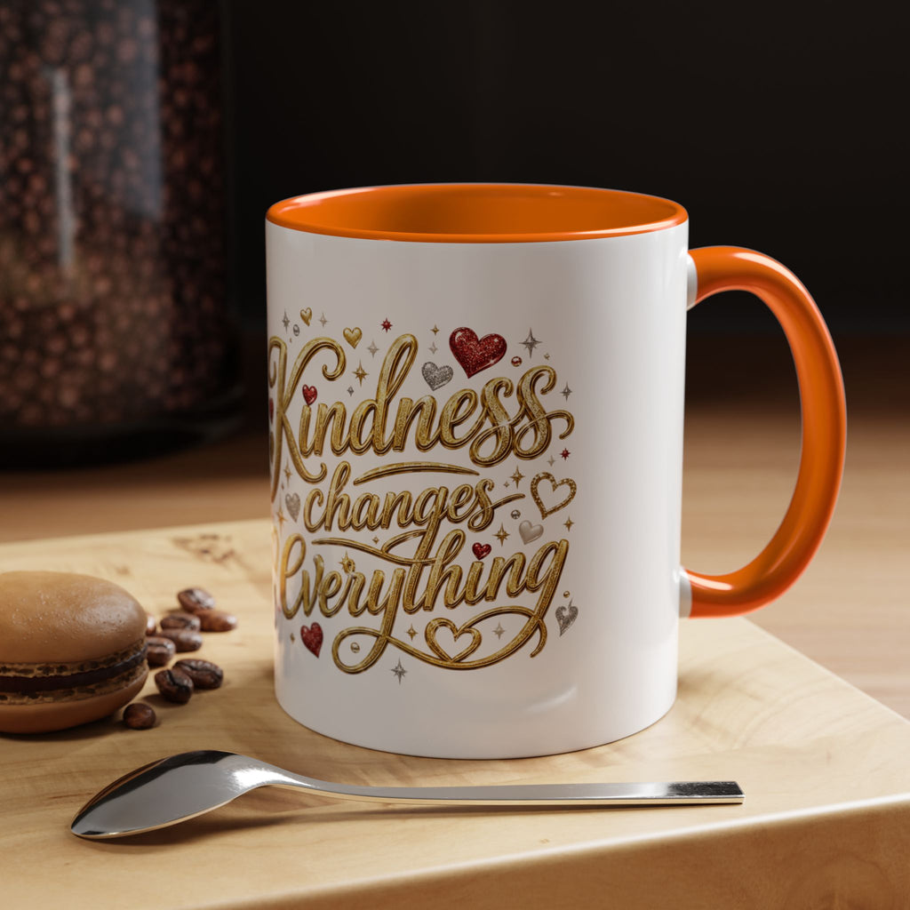 Inspirational ceramic coffee mug featuring the hand-lettered message “Kindness Changes Everything” with gold flourishes, hearts, and colorful accent handle and interior.