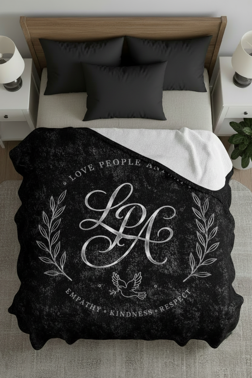 Black crushed velvet blanket featuring a vintage monogram, laurel wreath, and the words "Love People Anyway" in an elegant distressed design.