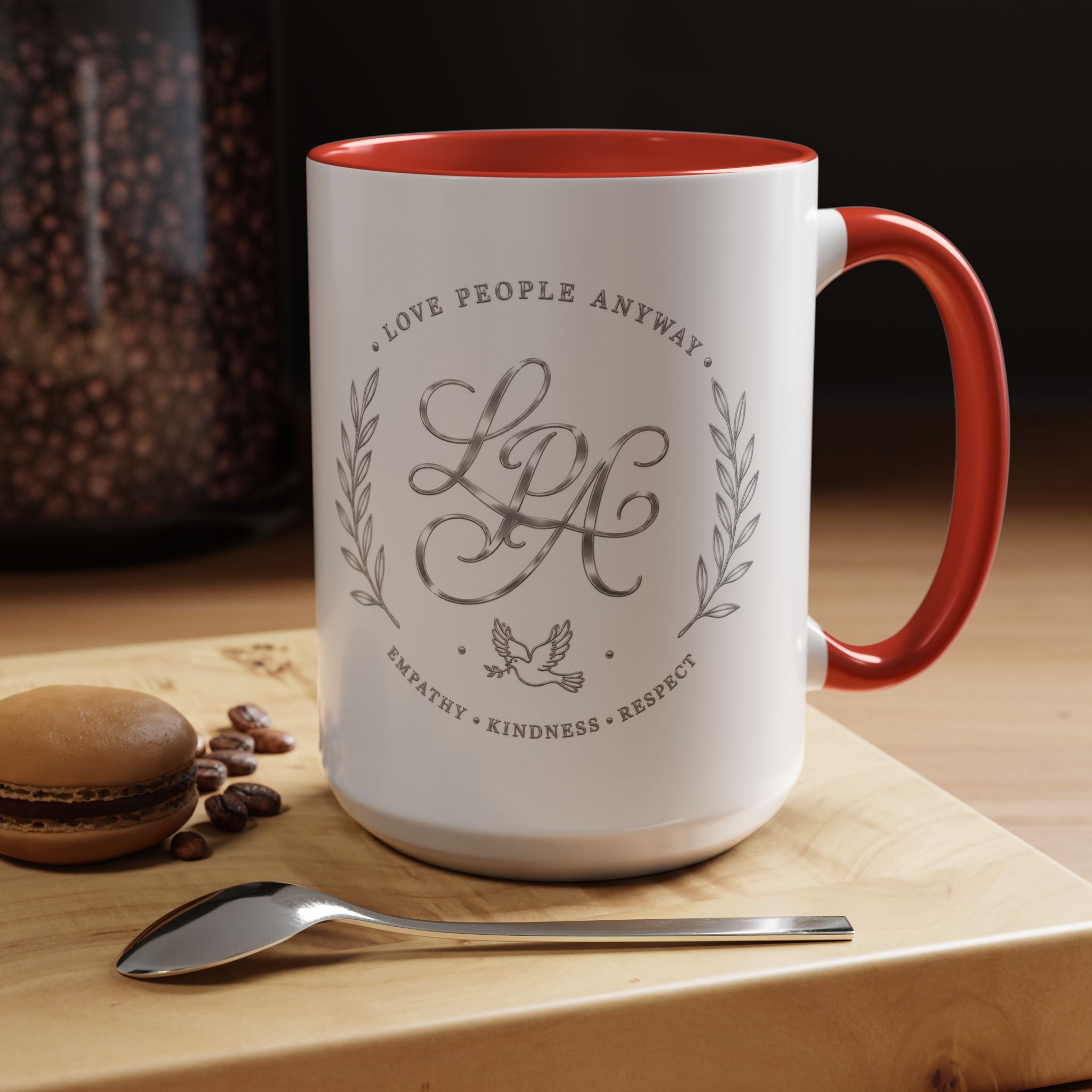 Inspirational ceramic coffee mug featuring silver “Love People Anyway” script, elegant monogram styling, decorative wreath accents, and contrasting handle and interior.