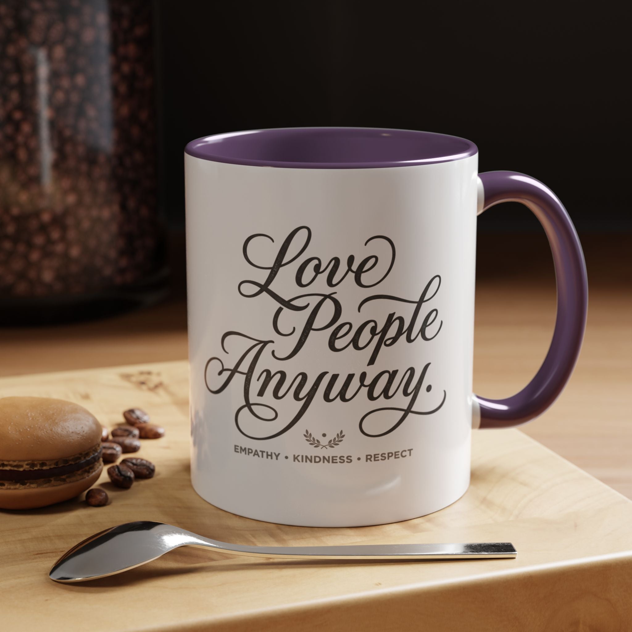 Inspirational ceramic accent coffee mug featuring hand-lettered “Love People Anyway” typography with empathy, kindness, and respect message on a glossy white mug with colorful handle and interior.