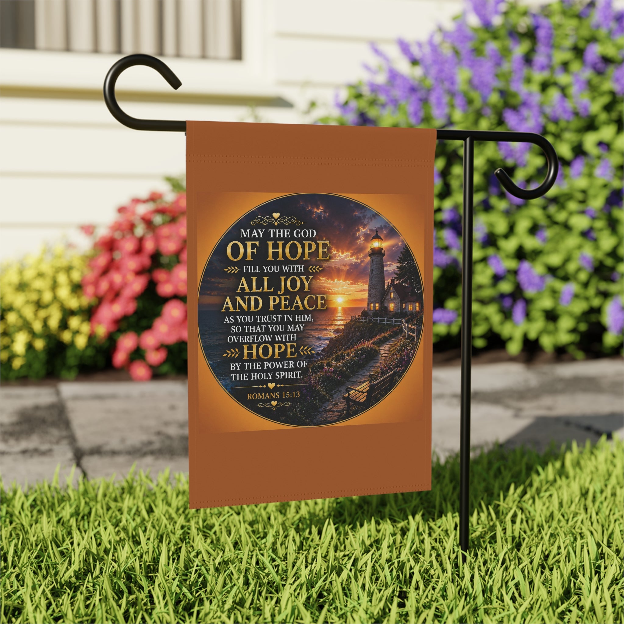 Inspirational Christian garden flag featuring a glowing lighthouse sunset with Romans 15:13 scripture artwork in warm coastal-inspired tones.