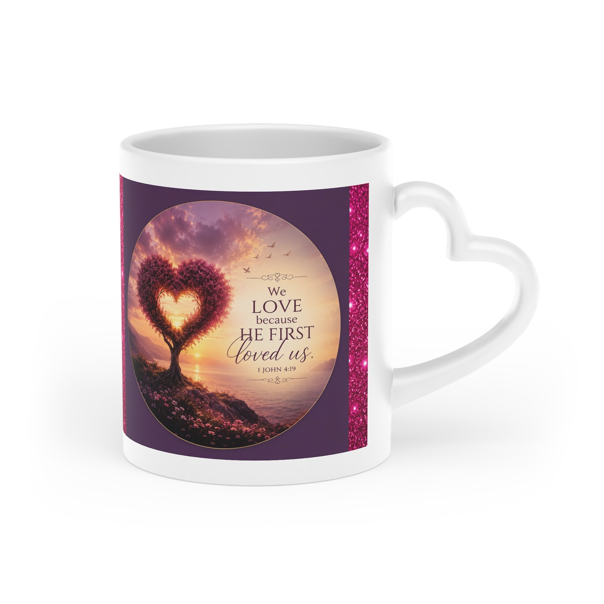White ceramic heart-shaped handle mug featuring a glowing heart-shaped tree at sunset with the Scripture "We Love Because He First Loved Us" from 1 John 4:19 in rich jewel-toned artwork.