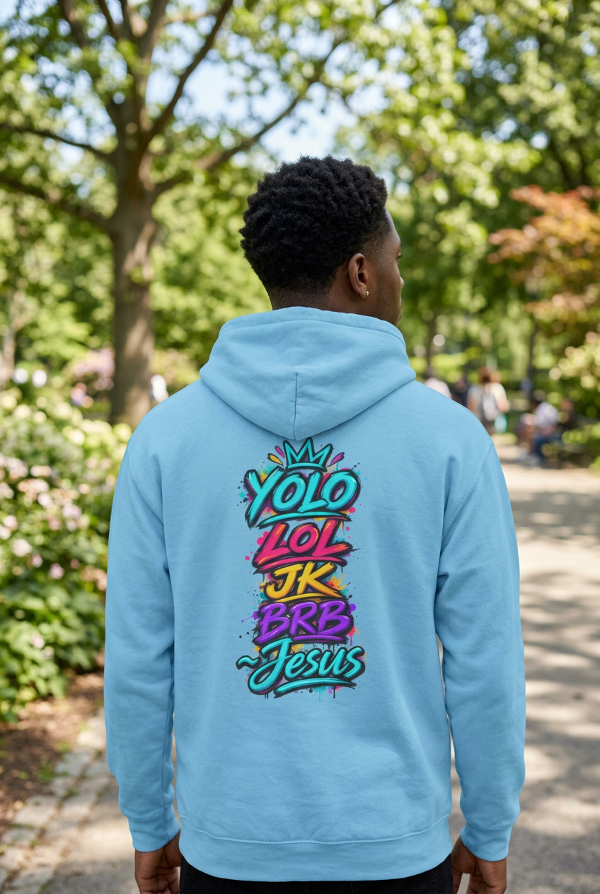 A light blue hoodie shown from the back, featuring a colorful graphic print with the text 'YOLO LOL JK BRB Jesus' in a graffiti-style font.