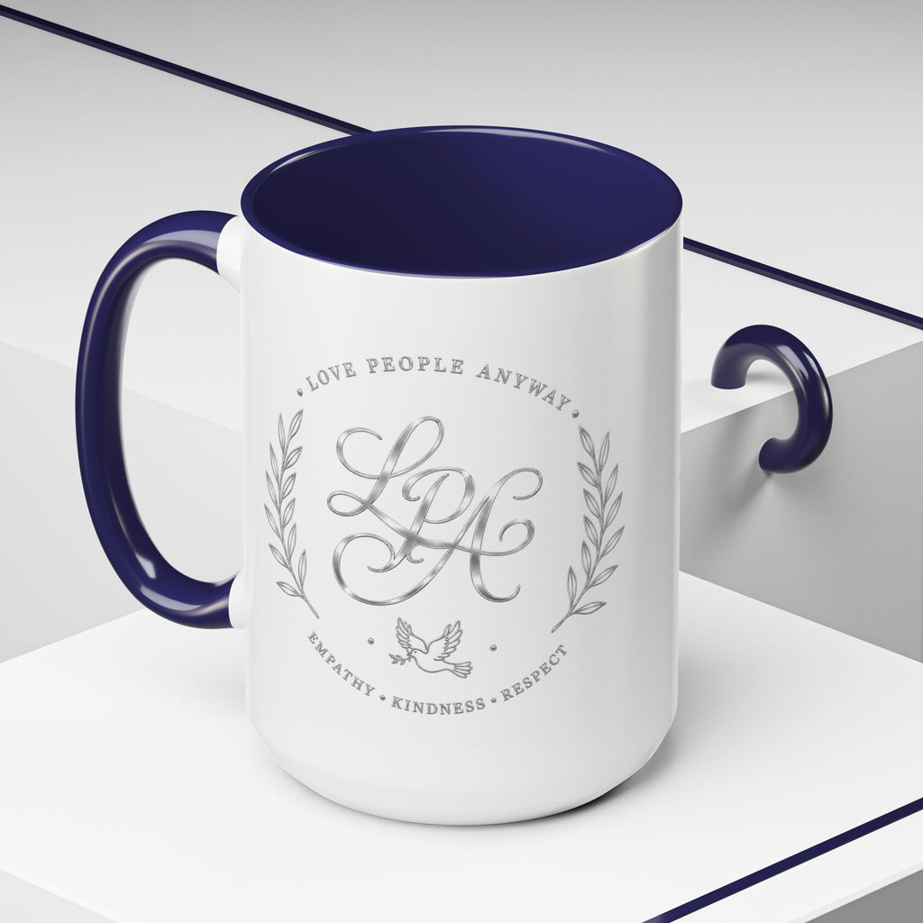 Inspirational ceramic coffee mug featuring silver “Love People Anyway” script, elegant monogram styling, decorative wreath accents, and contrasting handle and interior.