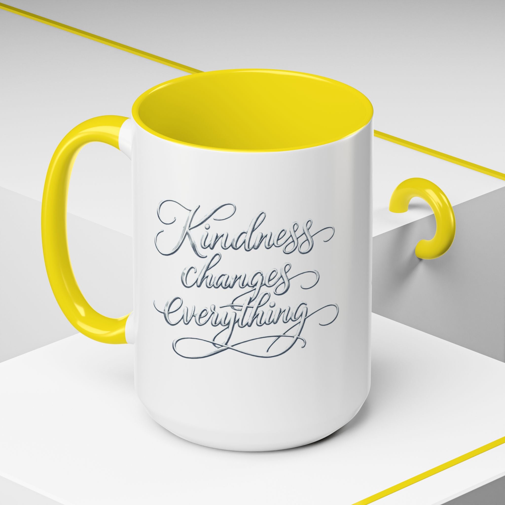 Inspirational ceramic accent coffee mug featuring elegant silver hand-lettered “Kindness Changes Everything” typography with colorful handle and interior accents.