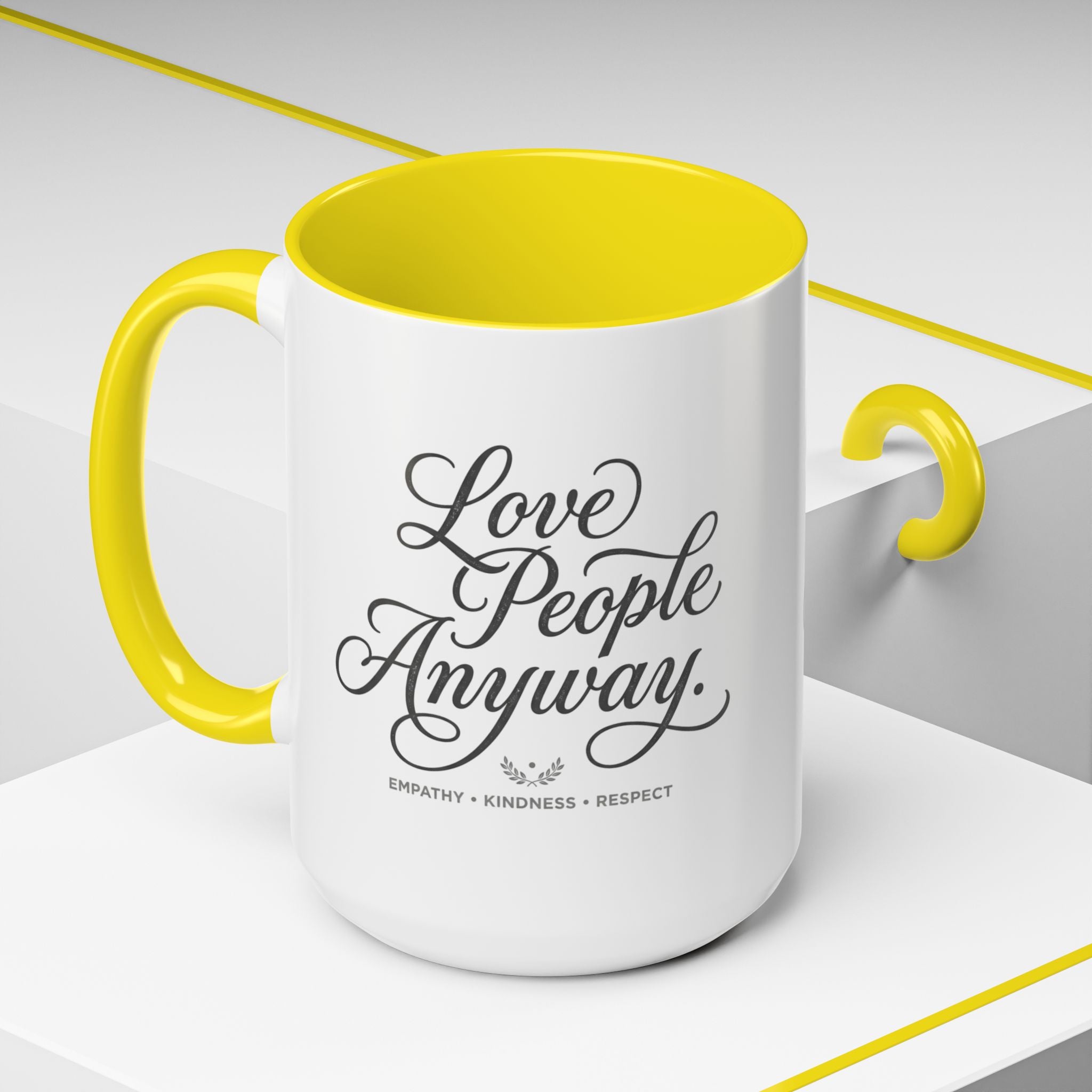 Inspirational ceramic accent coffee mug featuring hand-lettered “Love People Anyway” typography with empathy, kindness, and respect message on a glossy white mug with colorful handle and interior.