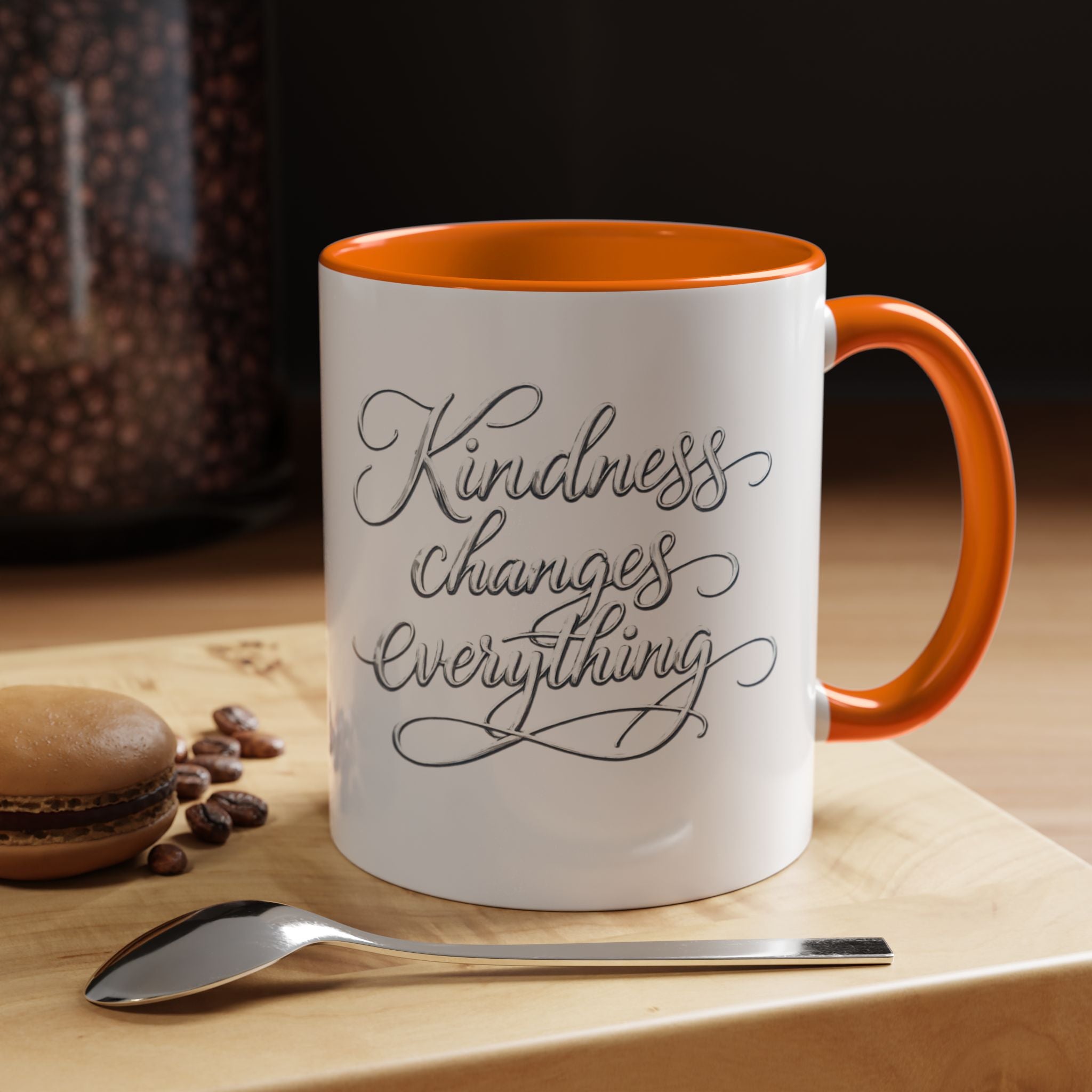 Inspirational ceramic accent coffee mug featuring elegant silver hand-lettered “Kindness Changes Everything” typography with colorful handle and interior accents.