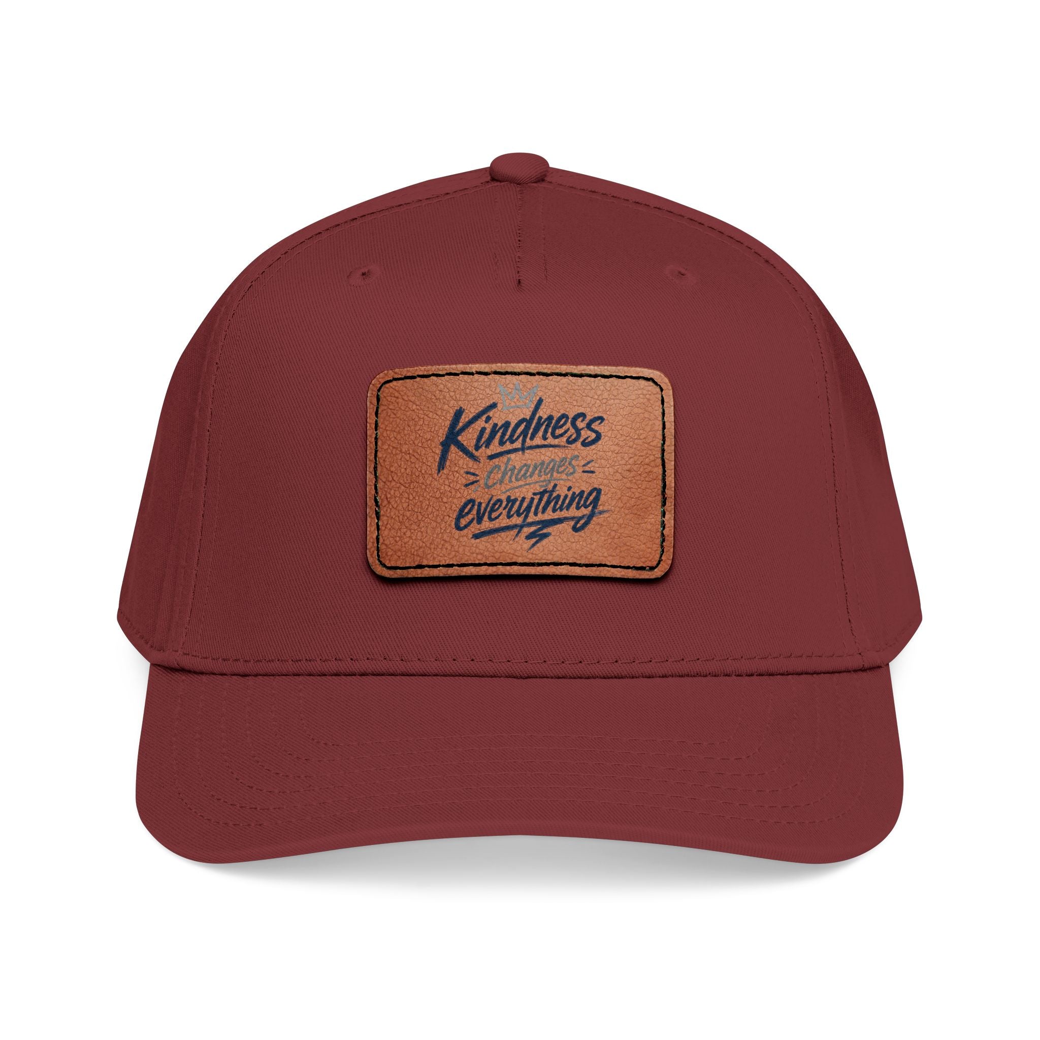 Vintage-inspired baseball cap featuring a brown leather patch with the phrase “Kindness Changes Everything” on a structured mid-profile snapback hat.