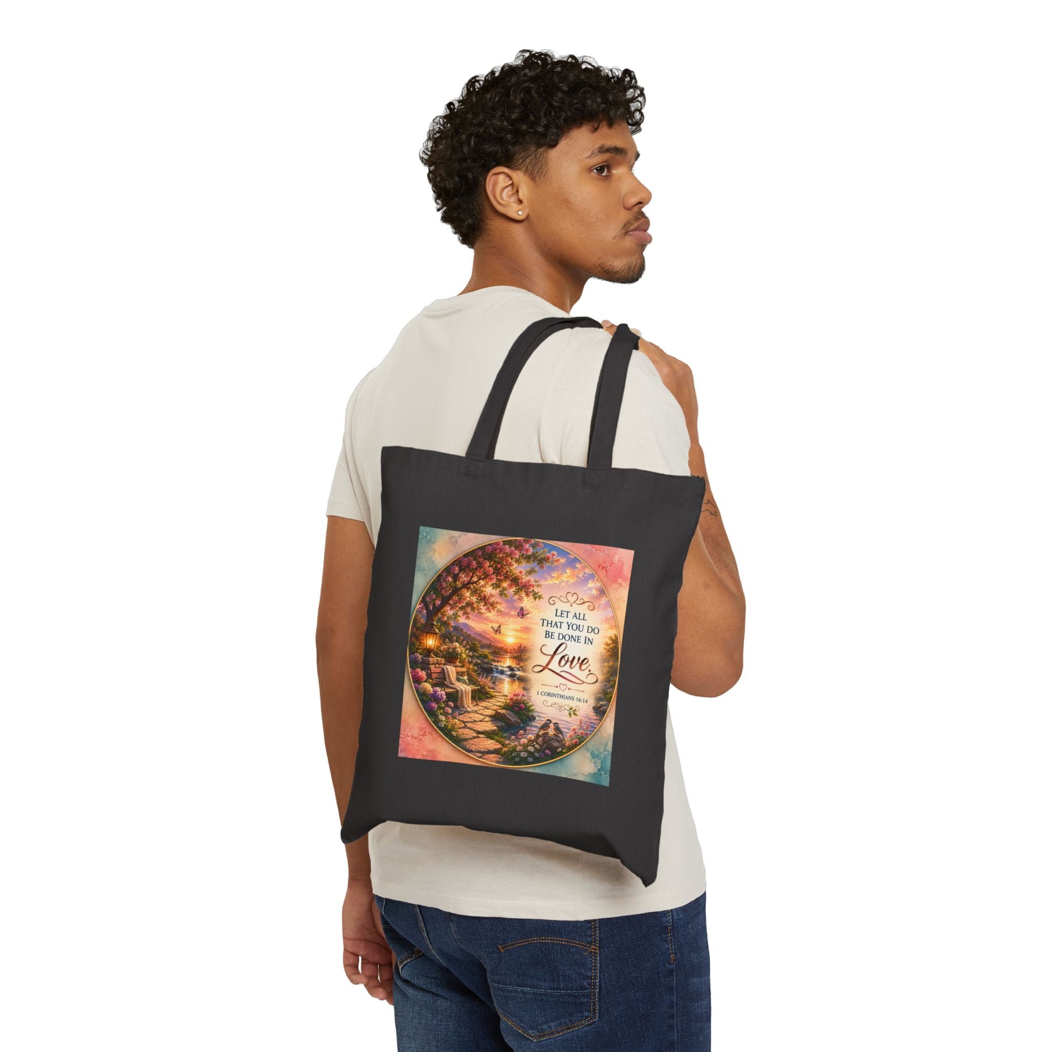 Christian cotton canvas tote bag featuring 1 Corinthians 16:14, “Let All That You Do Be Done in Love,” with a peaceful garden landscape, blooming flowers, butterflies, flowing river, lantern, birds, and sunset artwork.