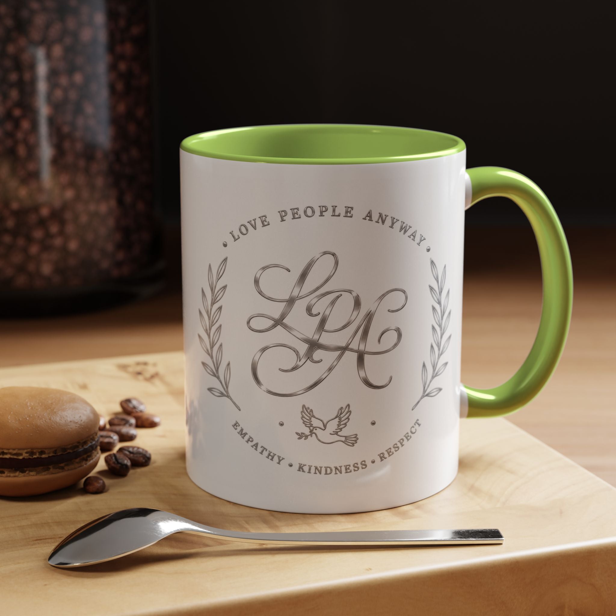 Inspirational ceramic coffee mug featuring silver “Love People Anyway” script, elegant monogram styling, decorative wreath accents, and contrasting handle and interior.