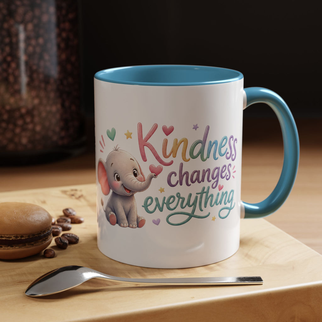 Cute ceramic coffee mug featuring a pastel baby elephant and the uplifting message “Kindness Changes Everything” with colorful accent handle and interior.