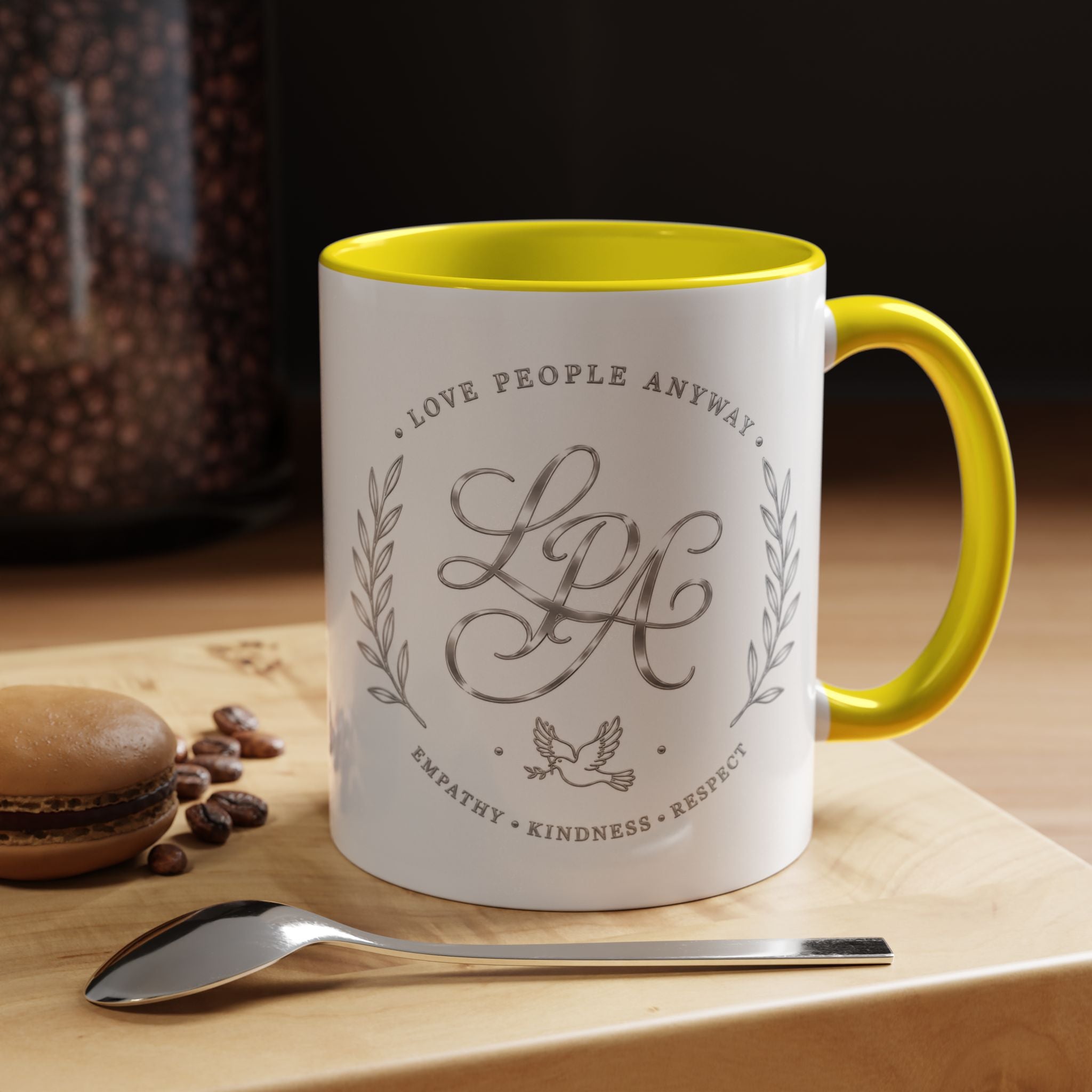 Inspirational ceramic coffee mug featuring silver “Love People Anyway” script, elegant monogram styling, decorative wreath accents, and contrasting handle and interior.