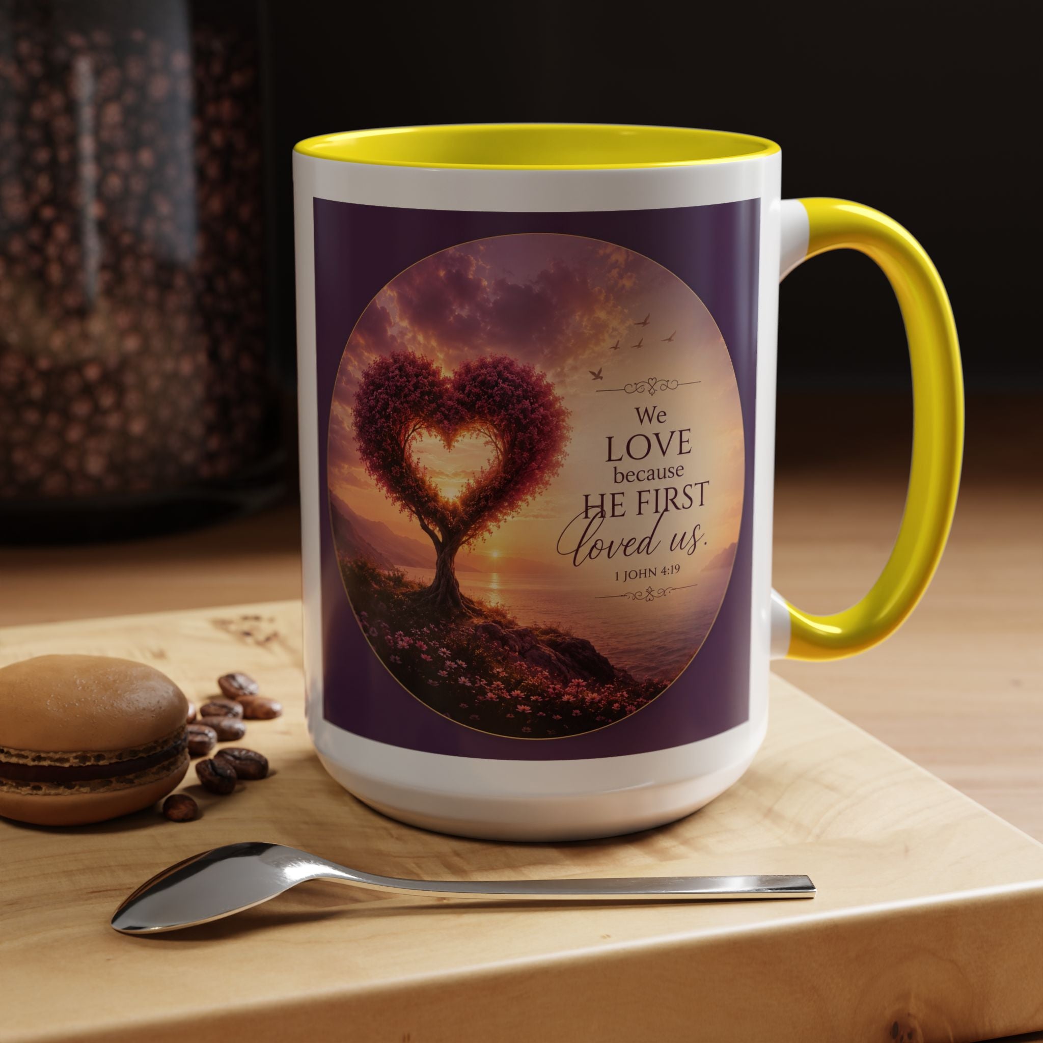 Inspirational Christian coffee mug featuring a glowing heart-shaped tree at sunset with the scripture “We Love Because He First Loved Us” from 1 John 4:19 and contrasting black handle and interior.