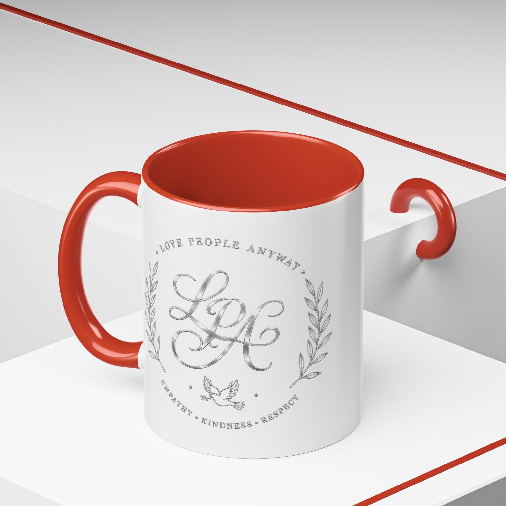 Inspirational ceramic coffee mug featuring silver “Love People Anyway” script, elegant monogram styling, decorative wreath accents, and contrasting handle and interior.