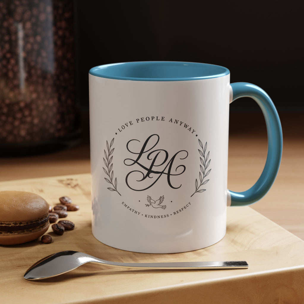 Personalized ceramic accent coffee mug featuring a custom monogram crest and the inspirational message “Love People Anyway” with colorful handle and interior accents.
