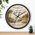 Inspirational Christian wall clock featuring Matthew 5:16 with a lantern-lit path, pine trees, rustic cottage, and warm countryside artwork in vintage farmhouse style.