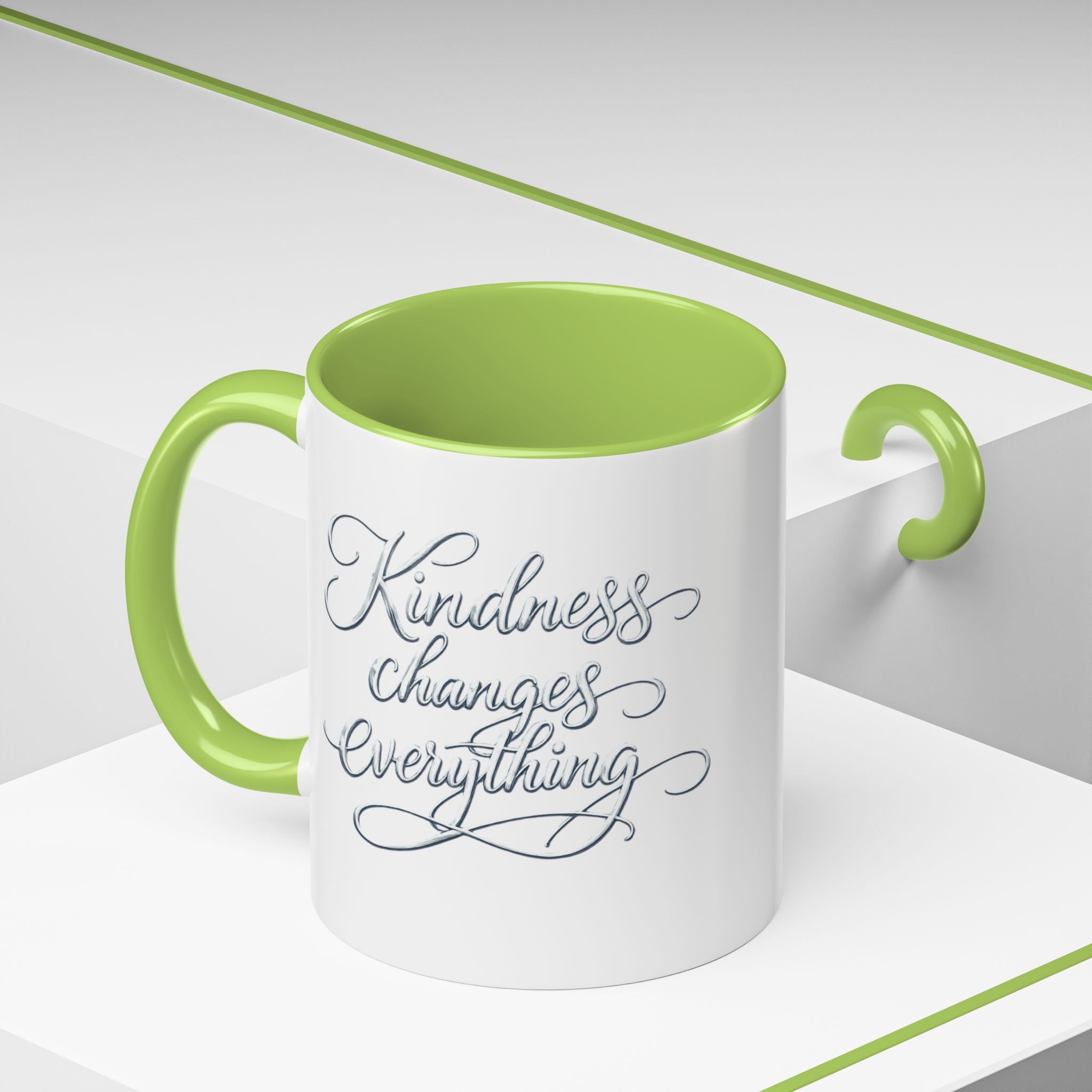 Inspirational ceramic accent coffee mug featuring elegant silver hand-lettered “Kindness Changes Everything” typography with colorful handle and interior accents.