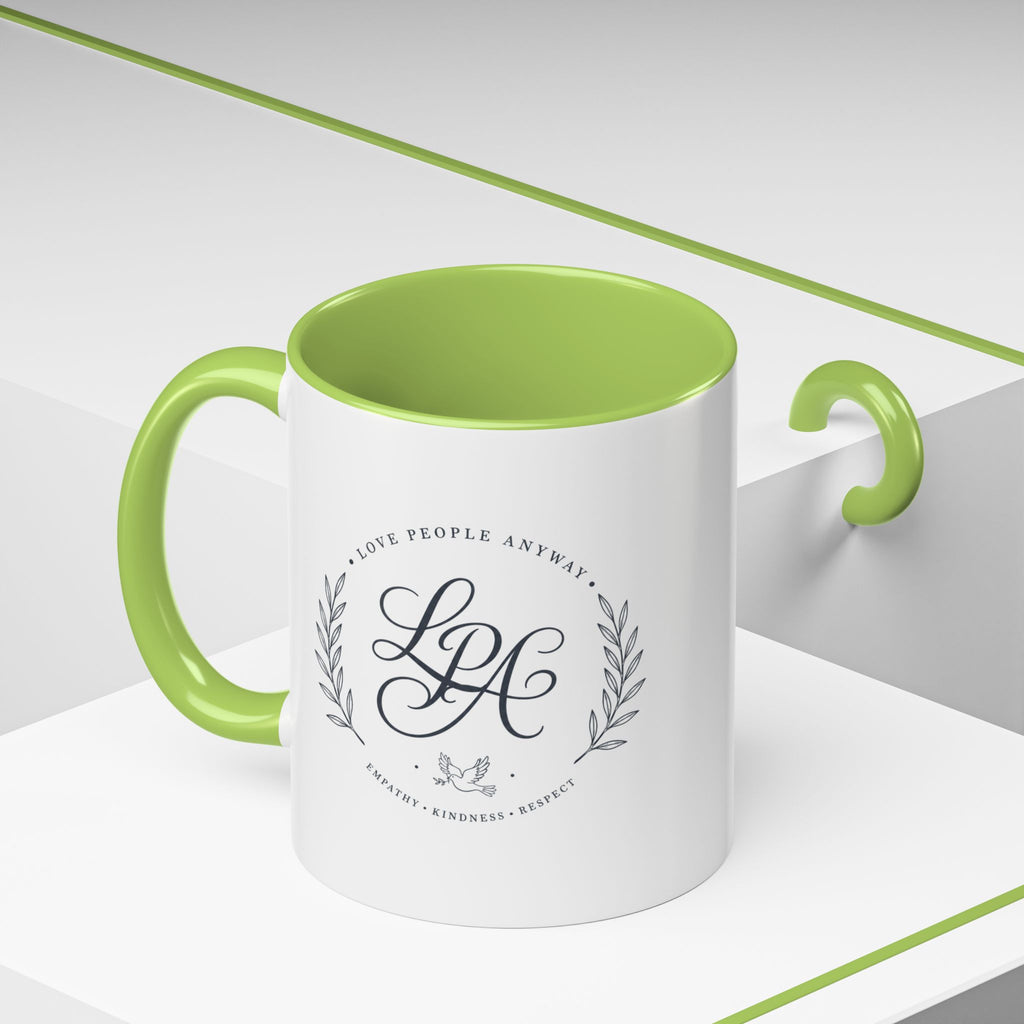 Personalized ceramic accent coffee mug featuring a custom monogram crest and the inspirational message “Love People Anyway” with colorful handle and interior accents.