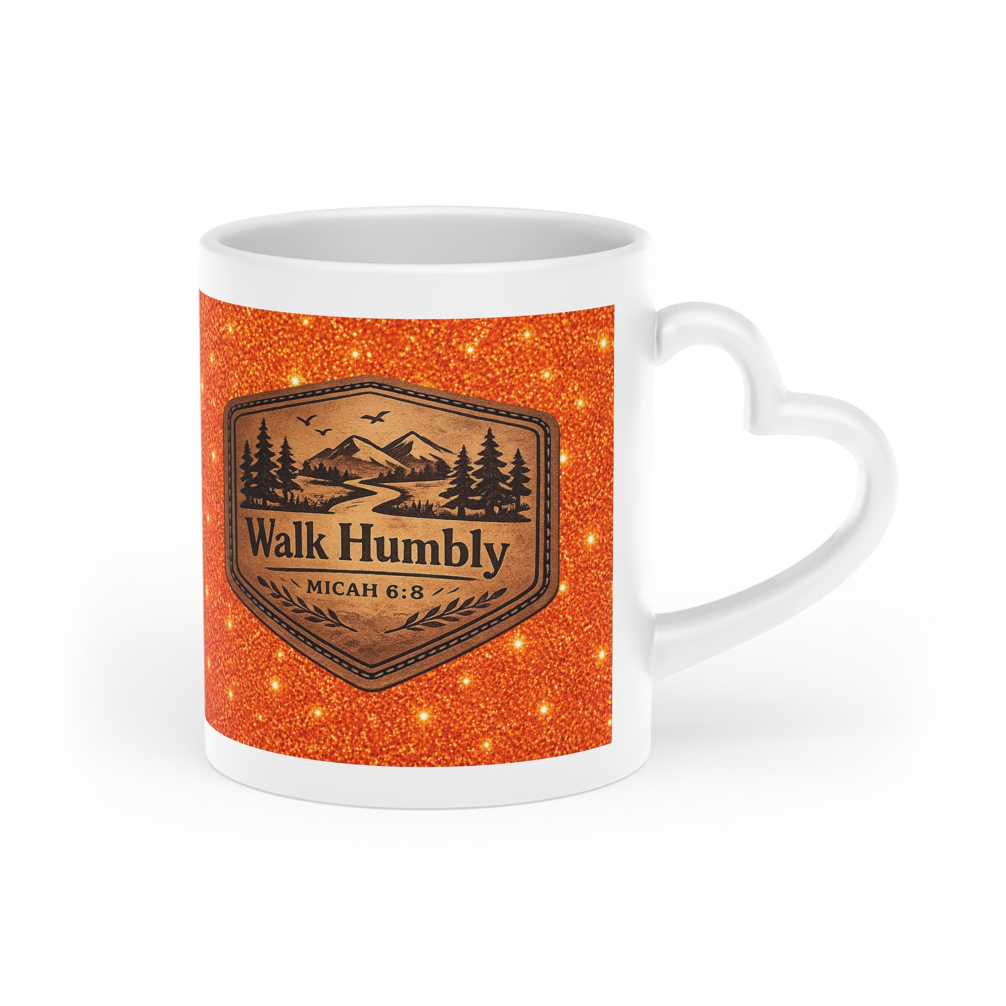 White ceramic heart-shaped handle mug featuring a rustic mountain "Walk Humbly" badge inspired by Micah 6:8 on a sparkling orange background.