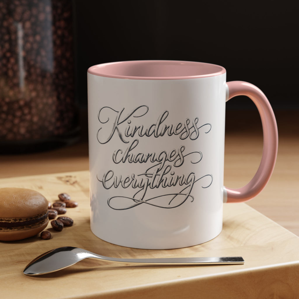 Inspirational ceramic accent coffee mug featuring elegant silver hand-lettered “Kindness Changes Everything” typography with colorful handle and interior accents.