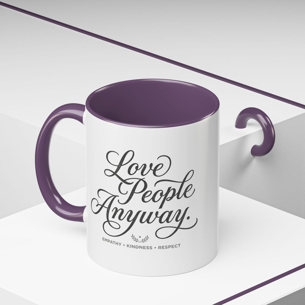 Inspirational ceramic accent coffee mug featuring hand-lettered “Love People Anyway” typography with empathy, kindness, and respect message on a glossy white mug with colorful handle and interior.