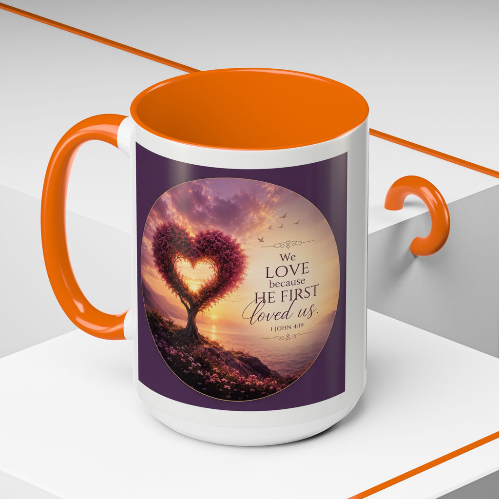 Inspirational Christian coffee mug featuring a glowing heart-shaped tree at sunset with the scripture “We Love Because He First Loved Us” from 1 John 4:19 and contrasting black handle and interior.