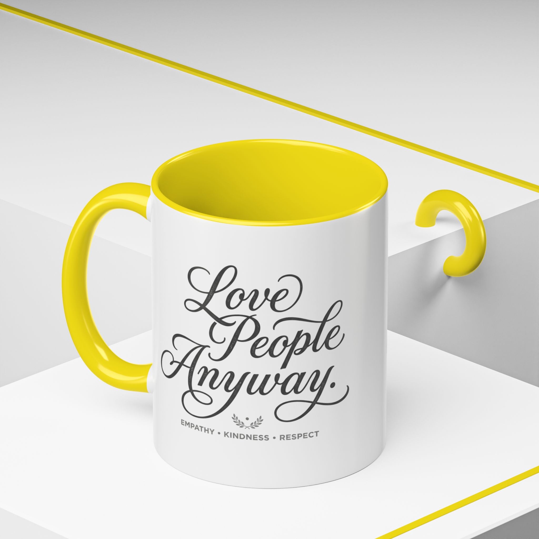 Inspirational ceramic accent coffee mug featuring hand-lettered “Love People Anyway” typography with empathy, kindness, and respect message on a glossy white mug with colorful handle and interior.