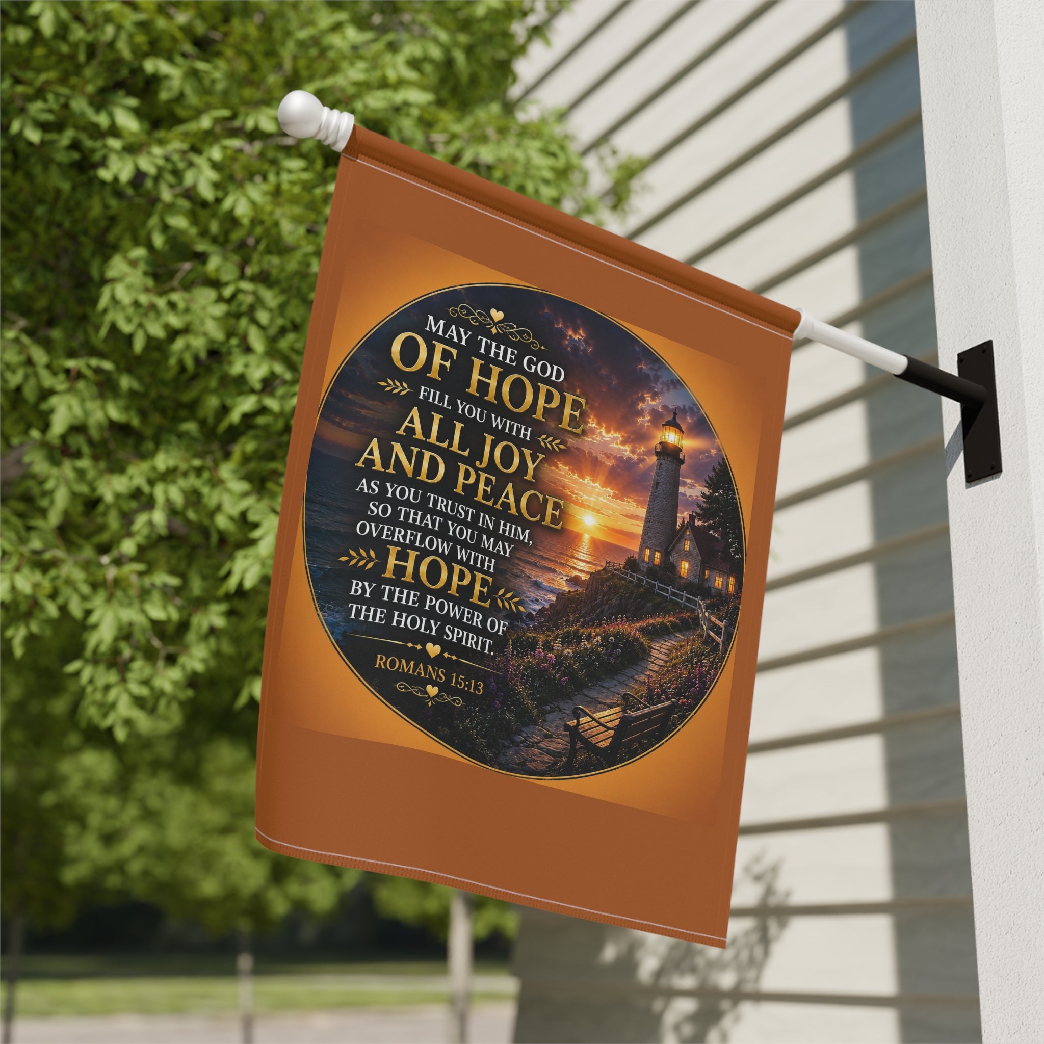 Inspirational Christian garden flag featuring a glowing lighthouse sunset with Romans 15:13 scripture artwork in warm coastal-inspired tones.