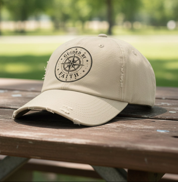 Vintage distressed Christian baseball cap featuring a compass emblem and the phrase “Guided by Faith” on a soft low-profile cotton twill hat.