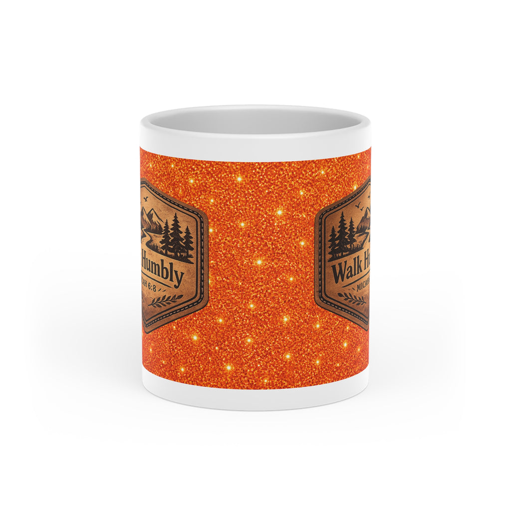 White ceramic heart-shaped handle mug featuring a rustic mountain "Walk Humbly" badge inspired by Micah 6:8 on a sparkling orange background.