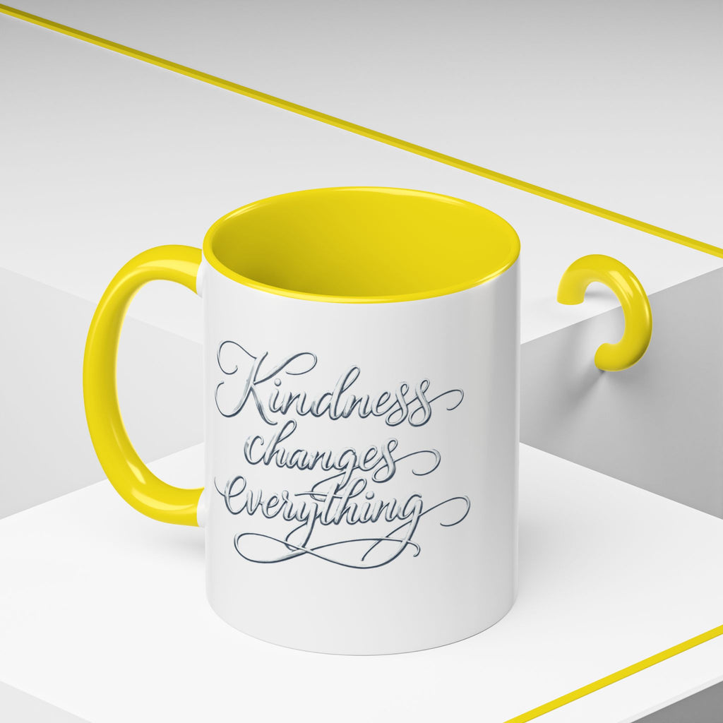 Inspirational ceramic accent coffee mug featuring elegant silver hand-lettered “Kindness Changes Everything” typography with colorful handle and interior accents.