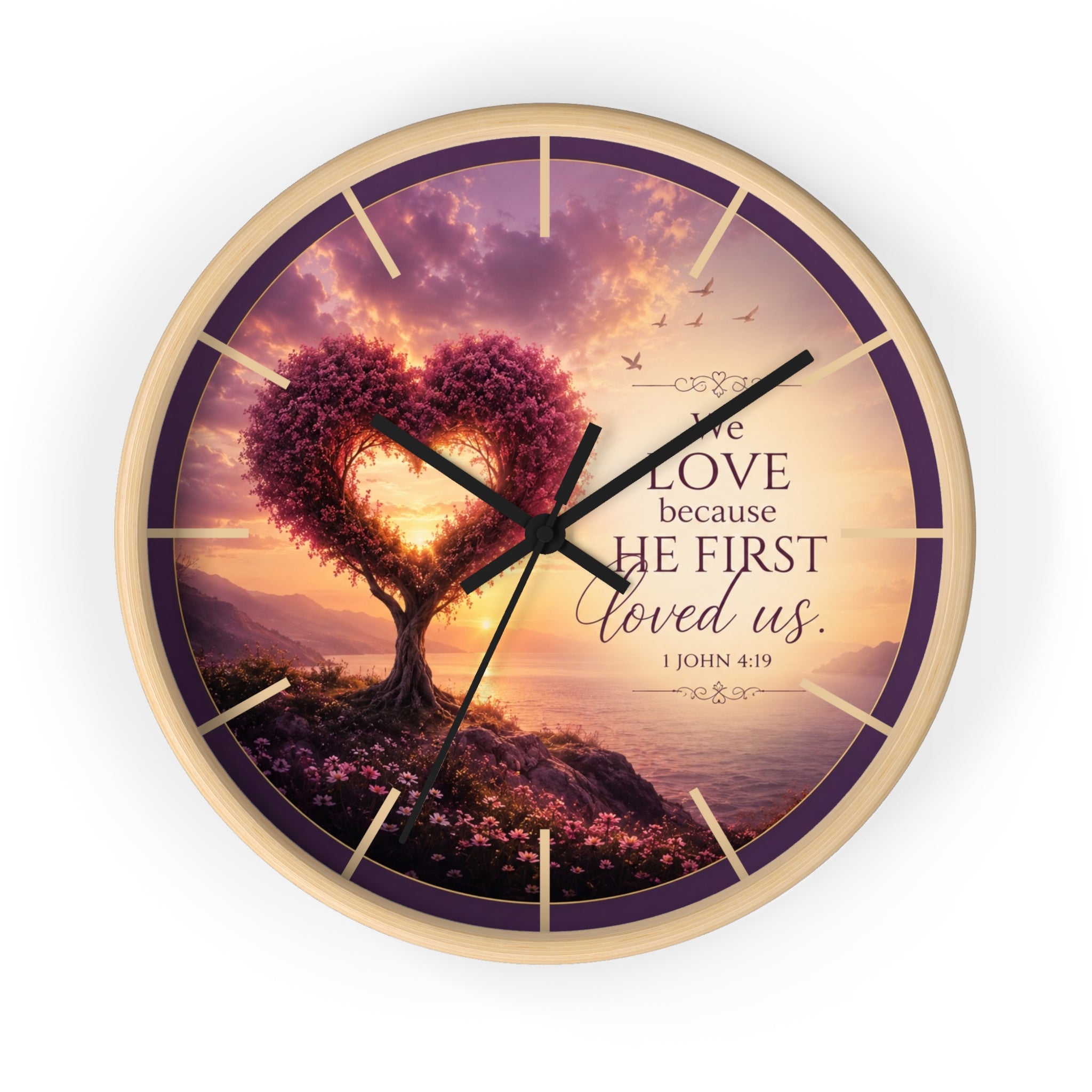 Inspirational Christian wall clock featuring a heart-shaped tree beside a peaceful shoreline sunset with 1 John 4:19 scripture about love and faith.