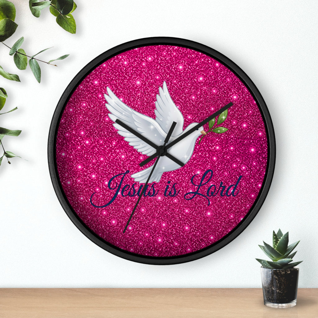 Round wall clock featuring a white dove carrying an olive branch with the words "Jesus Is Lord" on a sparkling pink background, finished with a wood frame and silent quartz movement.