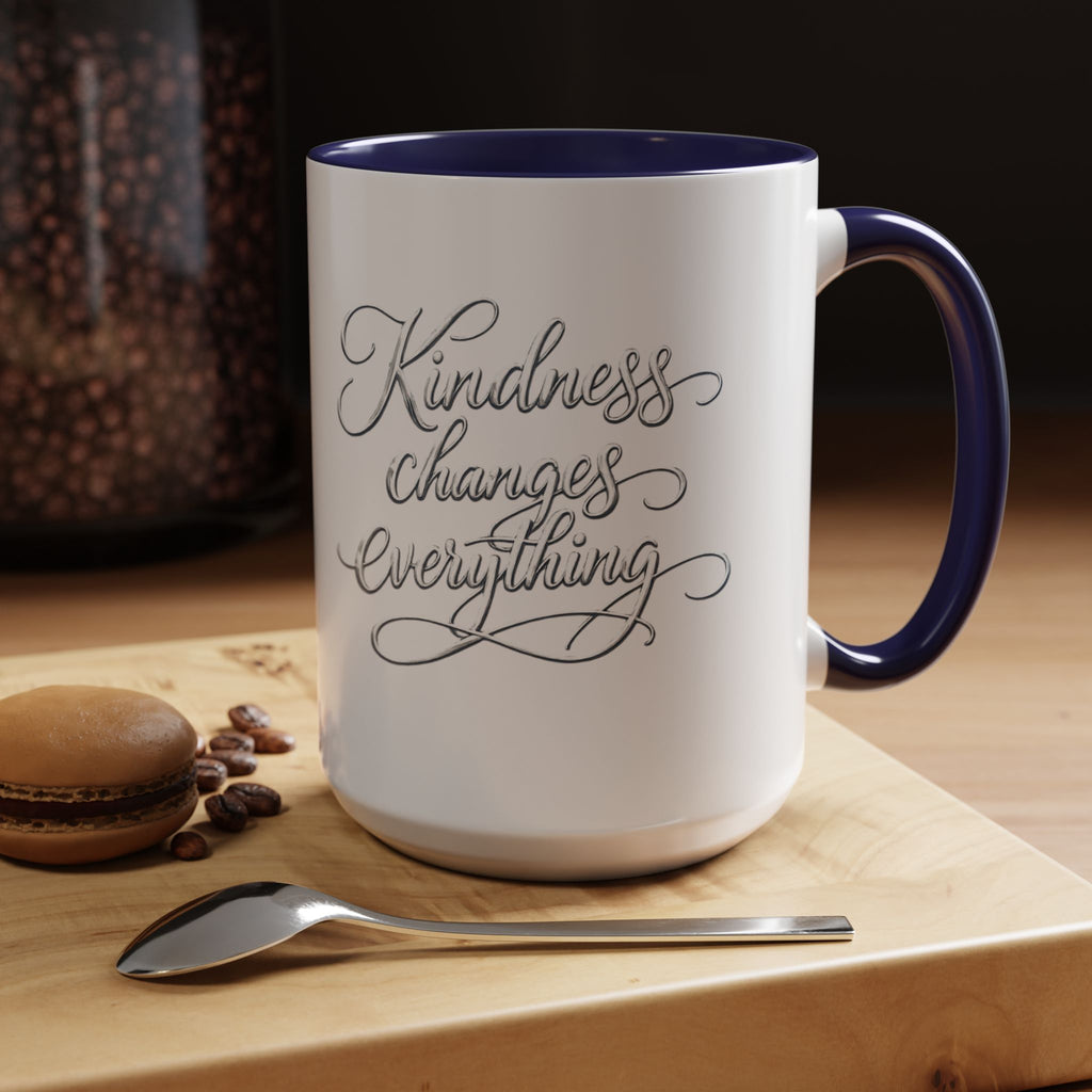 Inspirational ceramic accent coffee mug featuring elegant silver hand-lettered “Kindness Changes Everything” typography with colorful handle and interior accents.