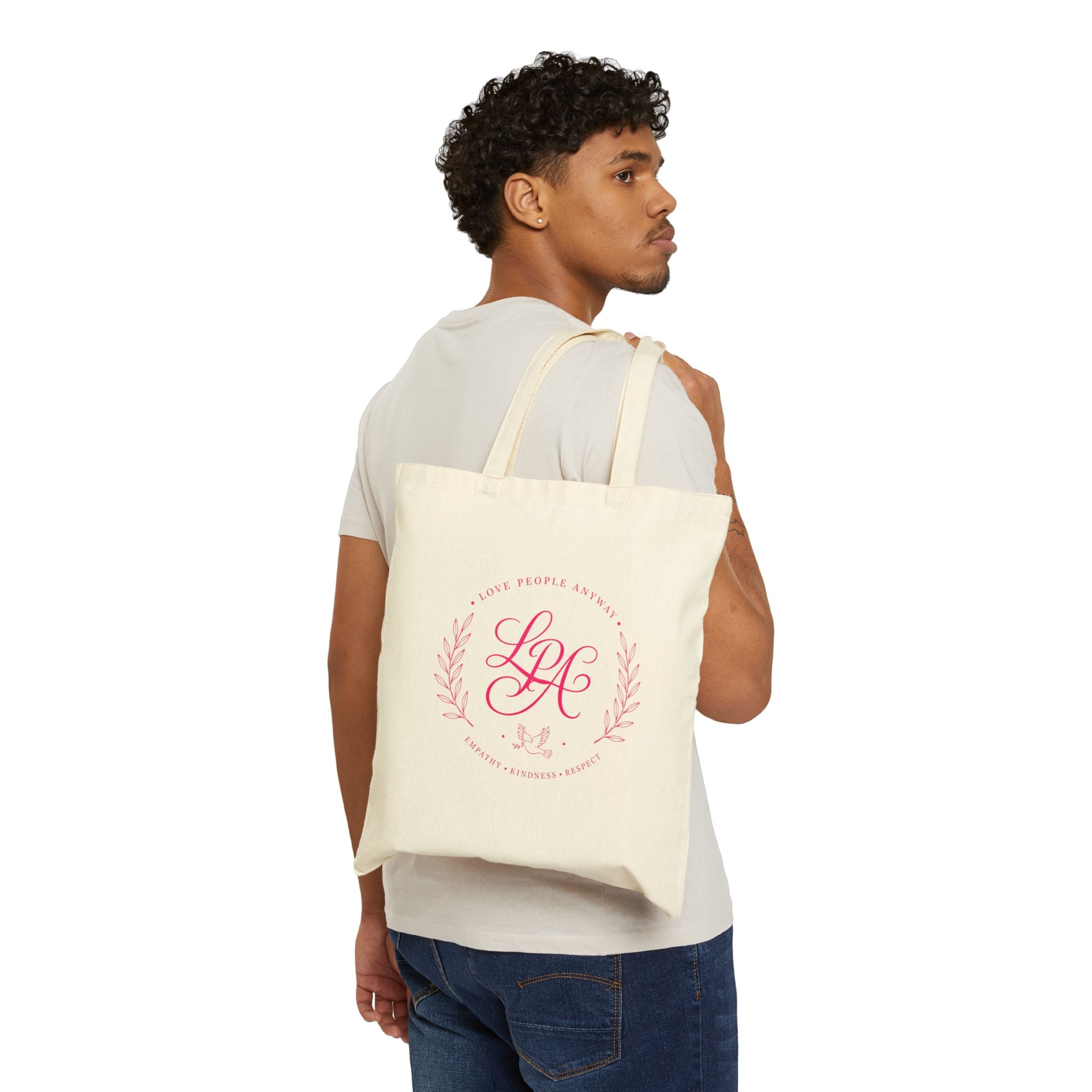 Pink monogram cotton canvas tote bag featuring the message “Love People Anyway,” laurel branches, a dove carrying an olive branch, and the words empathy, kindness, and respect in an elegant boutique design.