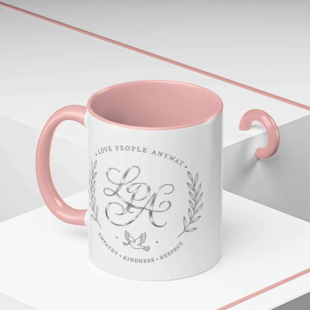Inspirational ceramic coffee mug featuring silver “Love People Anyway” script, elegant monogram styling, decorative wreath accents, and contrasting handle and interior.