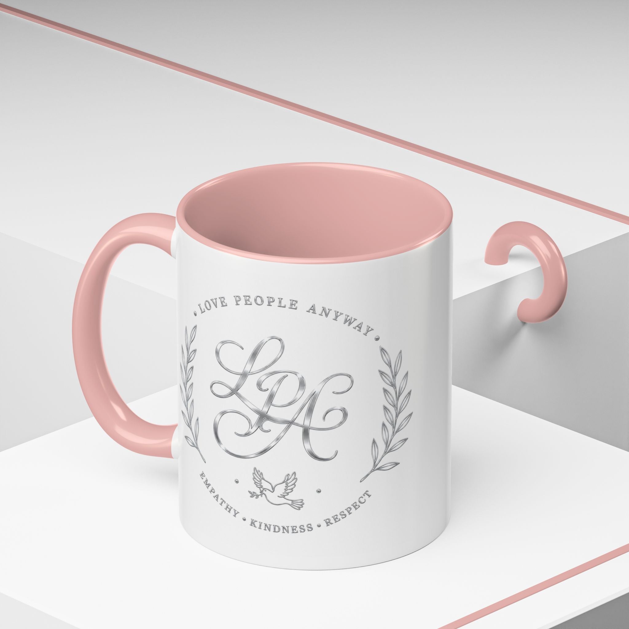 Inspirational ceramic coffee mug featuring silver “Love People Anyway” script, elegant monogram styling, decorative wreath accents, and contrasting handle and interior.