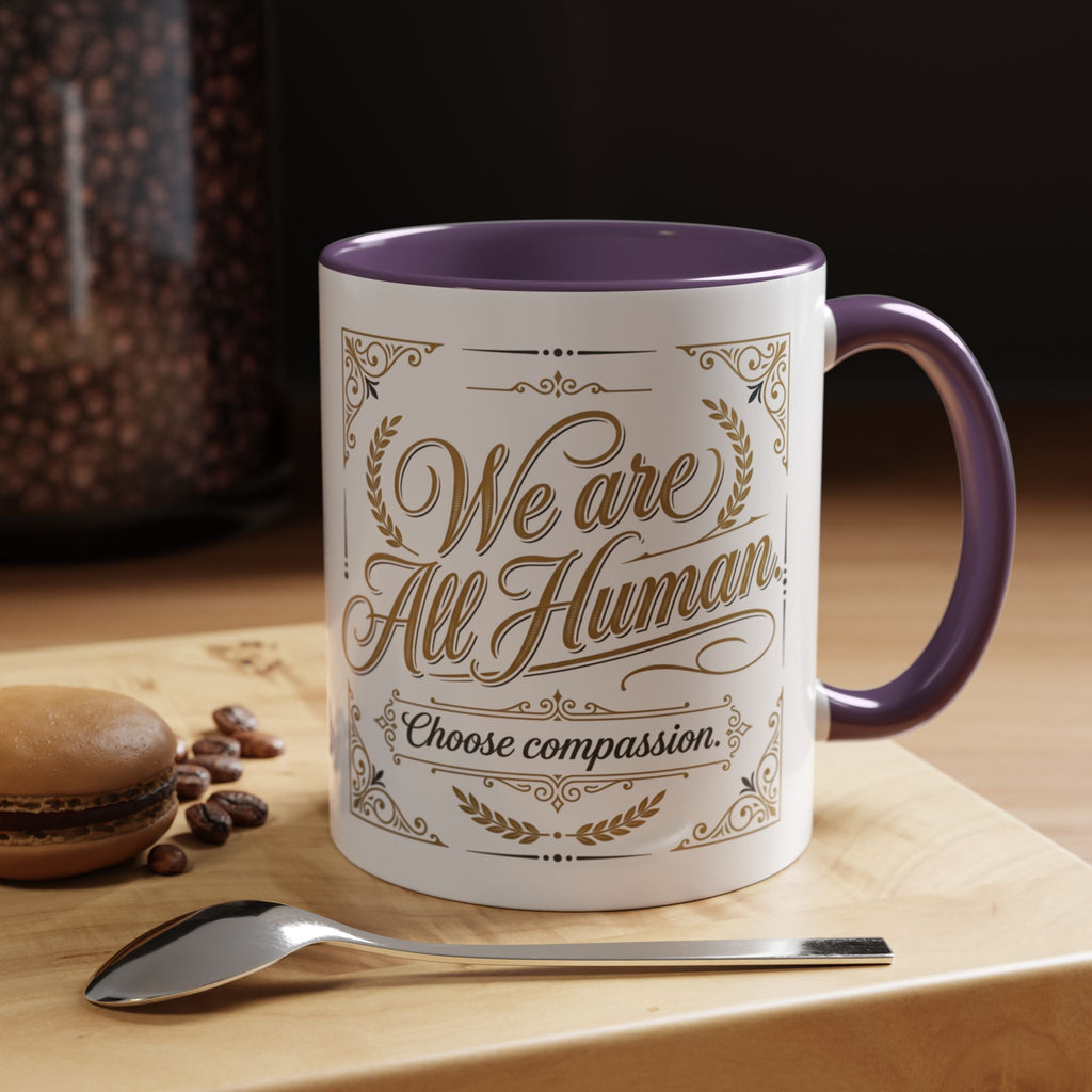 Inspirational ceramic accent coffee mug featuring “We Are All Human – Choose Compassion” in vintage-style gold lettering with decorative flourishes and black accent handle and interior.