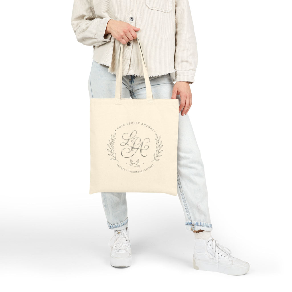 Elegant cotton canvas tote bag featuring a silver monogram crest, laurel branches, dove with olive branch, and the message “Love People Anyway” with empathy, kindness, and respect accents.